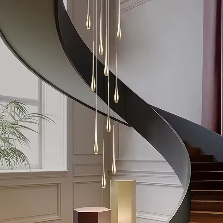 Au cœur d’un escalier en colimaçon, ce lustre cascade doré compose une silhouette élégante et contemporaine