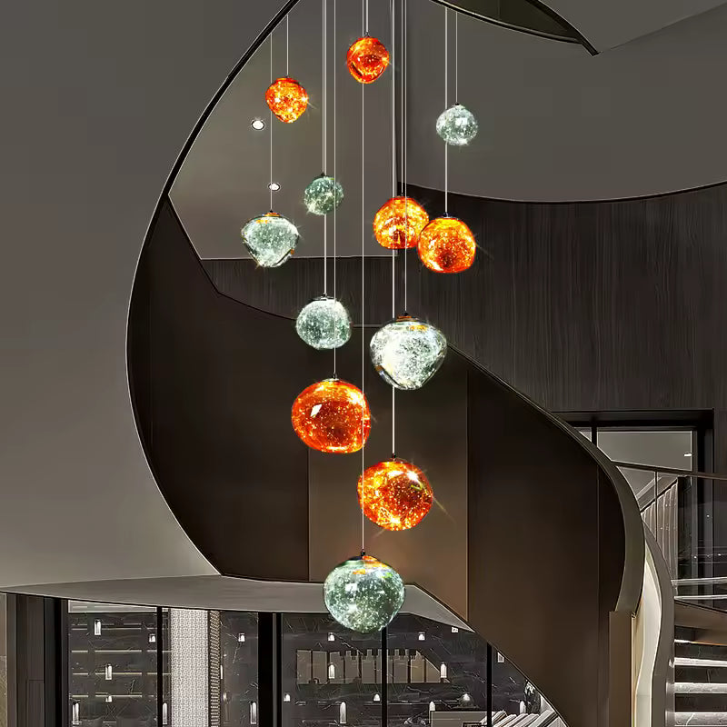 Au cœur d’un escalier hélicoïdal, un lustre monumental à boules lumineuses ambrées et argentées sublime un intérieur moderne.