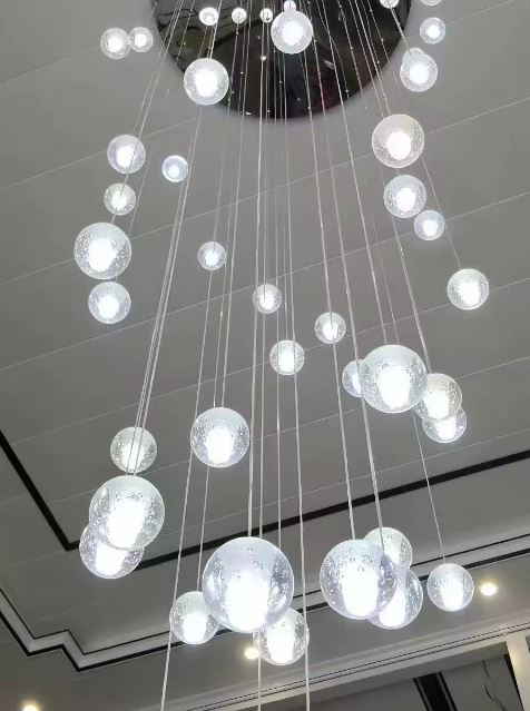 Lustre cascade de globes en verre bullé pour plafond haut, composition lumineuse contemporaine et spectaculaire.