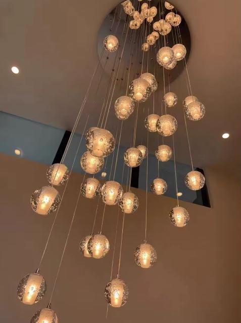 Lustre en cascade de globes en verre à lumière chaude, création lumineuse élégante pour plafond haut et intérieur raffiné.