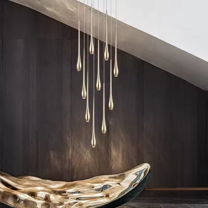 Des gouttes dorées élancées composent un lustre cascade au style contemporain, sculptural et luxueux