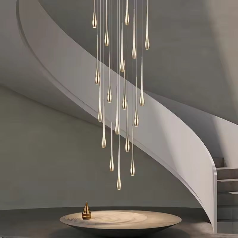 Dans une cage d’escalier, ce lustre cascade doré déploie des gouttes lumineuses au style sculptural et luxueux