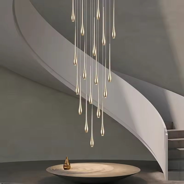 Dans une cage d’escalier, ce lustre cascade doré déploie des gouttes lumineuses au style sculptural et luxueux