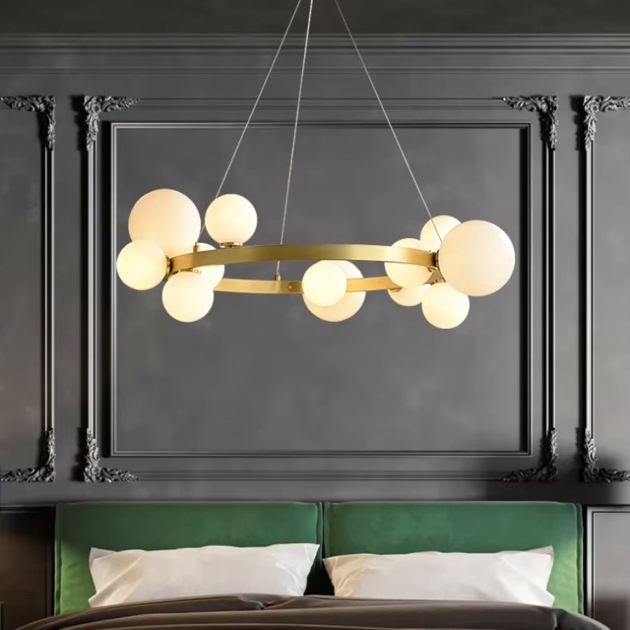 Au-dessus d'un lit à tête verte, un lustre doré à anneau circulaire et globes opalins sublime une chambre Art déco.