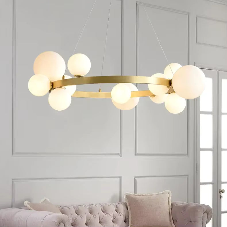 Dans un salon aux moulures élégantes, un lustre circulaire doré à globes opalins associe design moderne et style Art déco.
