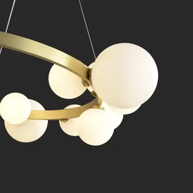 Vue rapprochée des globes lumineux en verre opalin d'un lustre circulaire doré au design géométrique et contemporain.