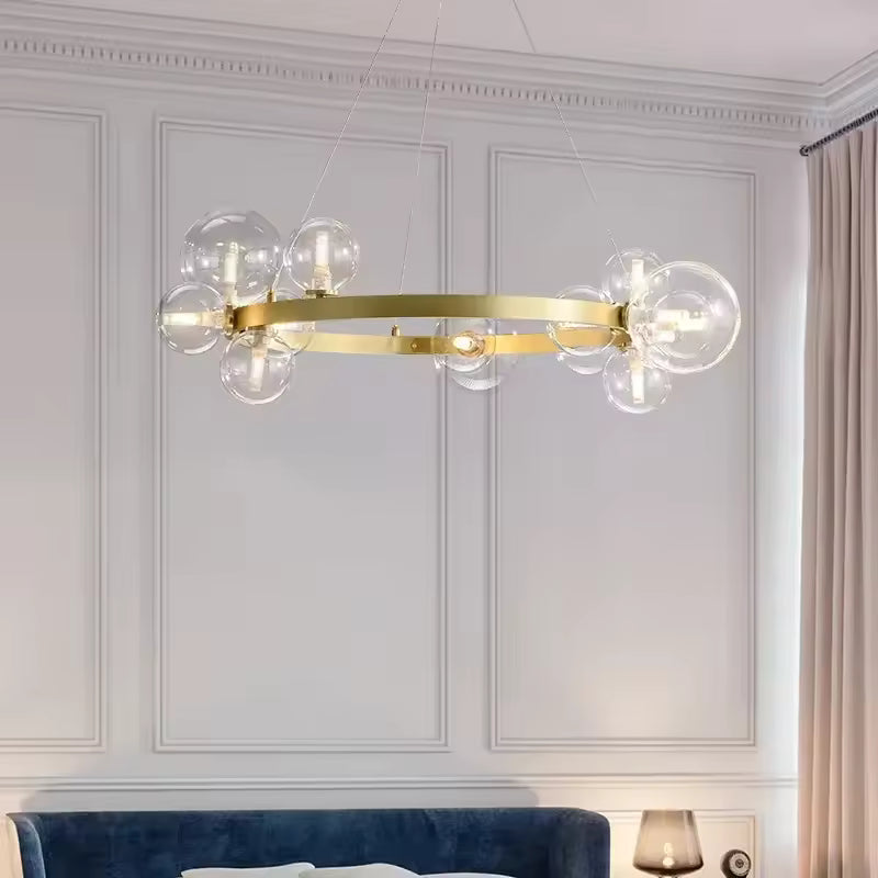 Un lustre circulaire doré aux globes en verre transparent surplombe un canapé bleu dans un salon élégant d'inspiration Art déco.