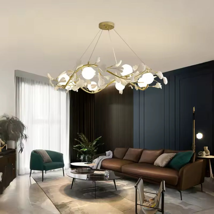 Dans un salon contemporain, lustre circulaire doré aux branches fleuries et globes opalins, au-dessus d'un canapé brun.