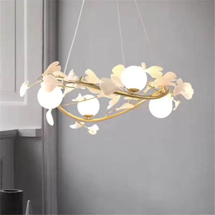 Branches dorées entrelacées et fleurs blanches entourent les globes opalins de ce lustre circulaire au design organique.