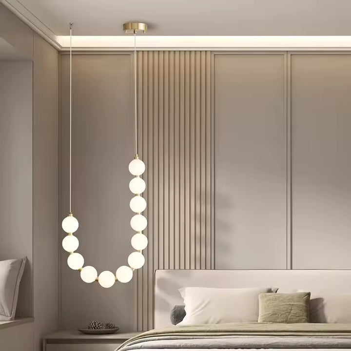 En version épurée, ce collier de globes lumineux crée une suspension élégante et contemporaine dans la chambre