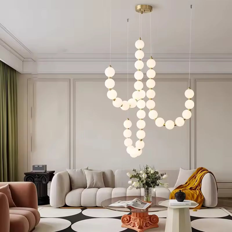 Au cœur d’un salon contemporain, ce lustre de globes lumineux blancs et dorés crée une composition sculpturale