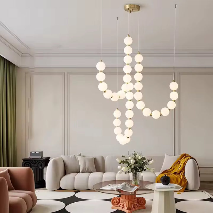 Au cœur d’un salon contemporain, ce lustre de globes lumineux blancs et dorés crée une composition sculpturale