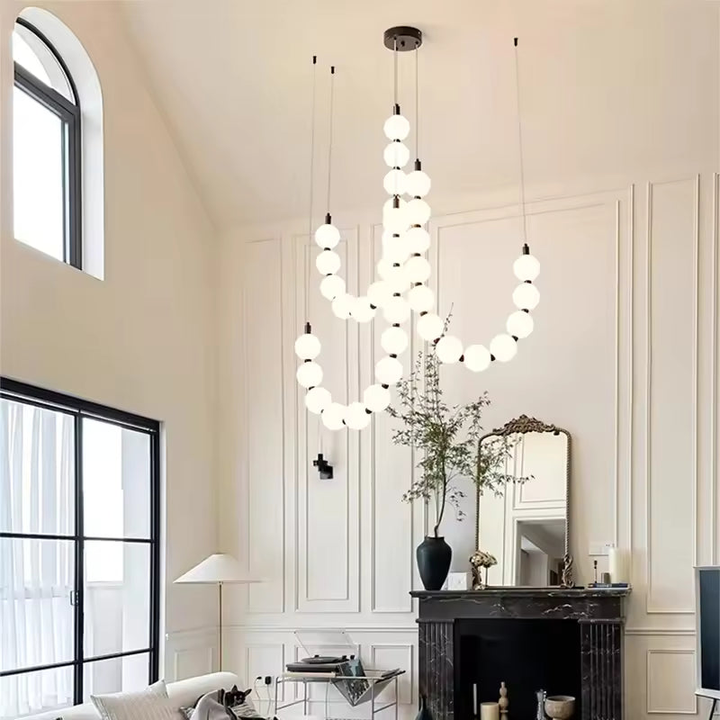 Dans un salon à plafond haut, ce lustre de globes lumineux crée une composition aérienne au style contemporain