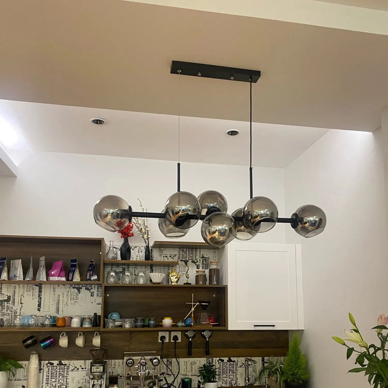 Lustre linéaire contemporain multi-globes en verre fumé dans un aménagement intérieur soigné.