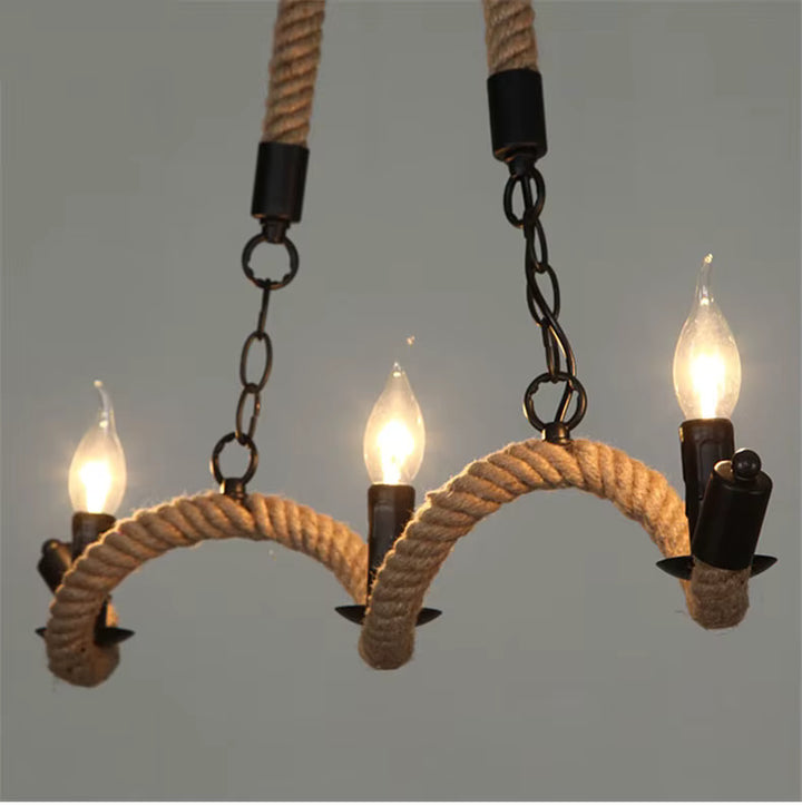 Vue rapprochée d'un lustre en corde de chanvre aux bras courbés, avec trois ampoules flammes et fixations noires.