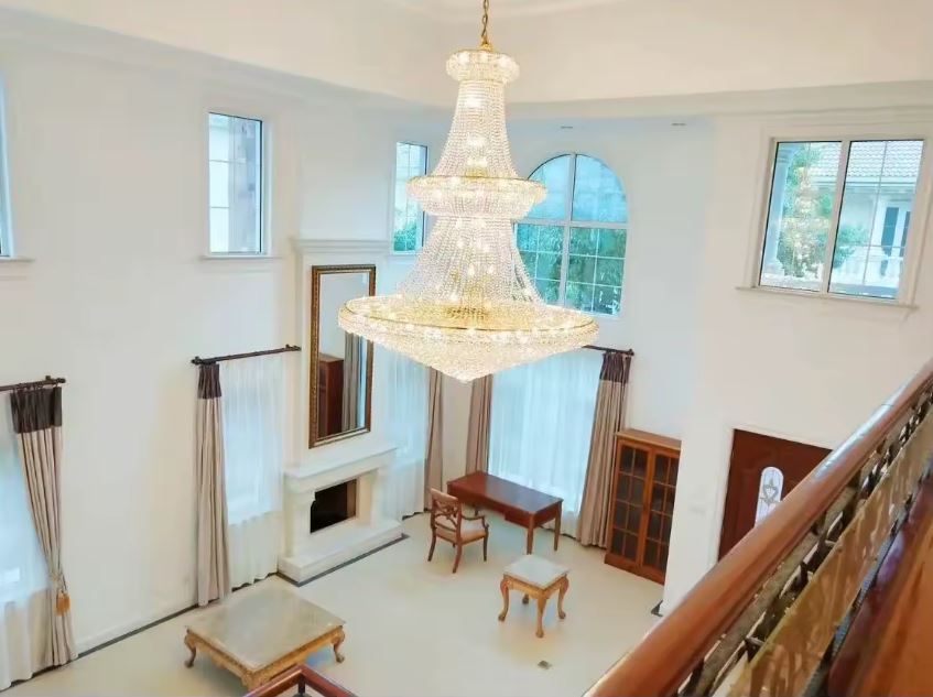 Lustre en cristal en cascade pour vide sur séjour, style classique prestige dans une pièce à plafond haut.