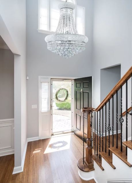 Lustre en cristal suspendu dans une entrée avec escalier, style classique raffiné pour belle hauteur sous plafond.