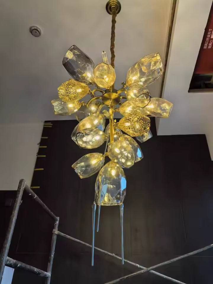 Vue en contre-plongée d’un lustre en cristal fumé et doré, composé en cascade verticale au style luxueux et sculptural.