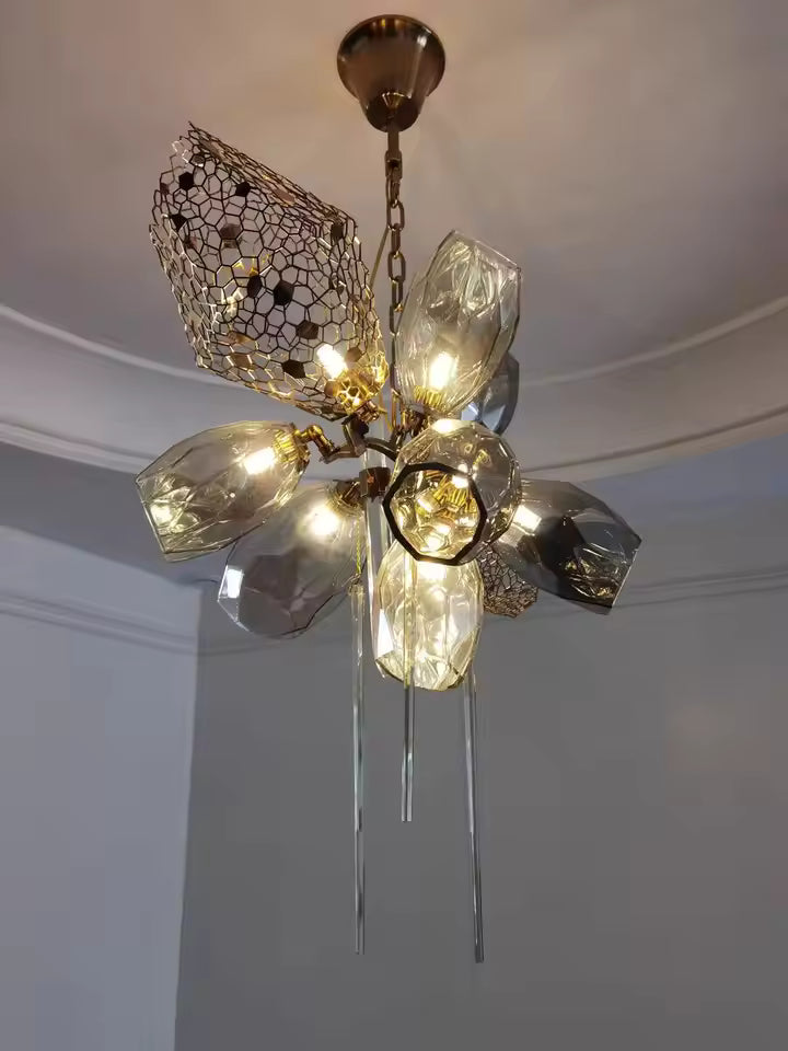 Lustre en cristal fumé aux formes facettées, avec résille dorée ajourée et pampilles fines dans un esprit précieux et sculptural.