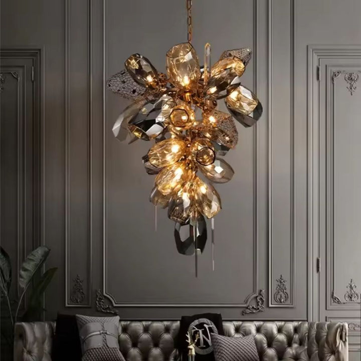 Suspendu dans un salon chic, ce lustre en cristal fumé et doré adopte une silhouette verticale au style sculptural raffiné.