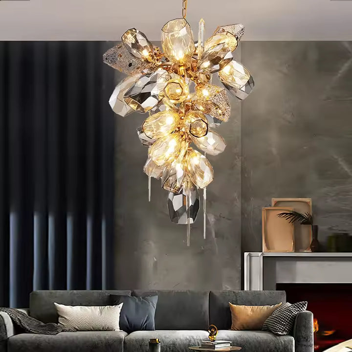 Lustre vertical en cristal fumé et doré, composé de facettes lumineuses et pampilles dans un salon chic contemporain.