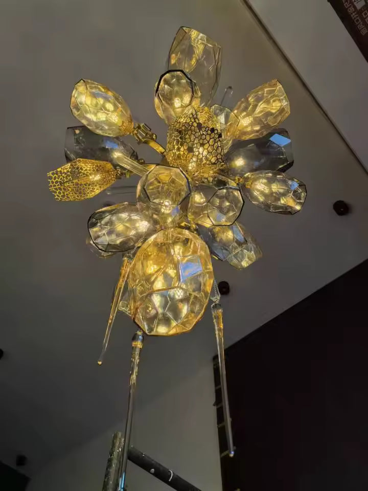 Vue du dessous d’un lustre en cristal fumé et doré, aux volumes facettés et pampilles élancées de style sculptural.