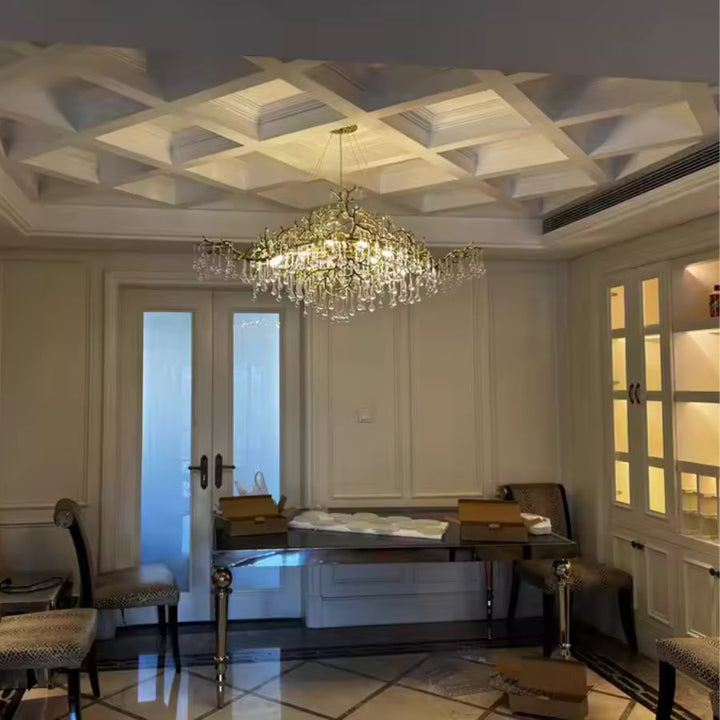 Au centre de cette pièce classique, le lustre en cristal déploie ses pampilles sur une structure dorée sculpturale