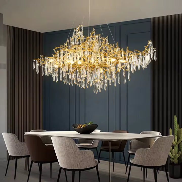 Au-dessus de la table, ce lustre à pampilles de cristal et branches dorées compose une allure raffinée et sculpturale