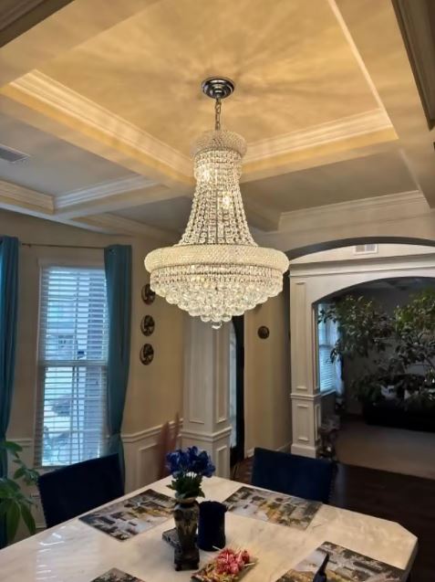 Lustre en cristal suspendu dans une salle à manger, style classique chic et éclat raffiné sous plafond travaillé.