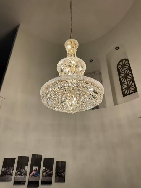 Lustre en cristal suspendu en hauteur, entre élégance classique et mise en scène contemporaine lumineuse.