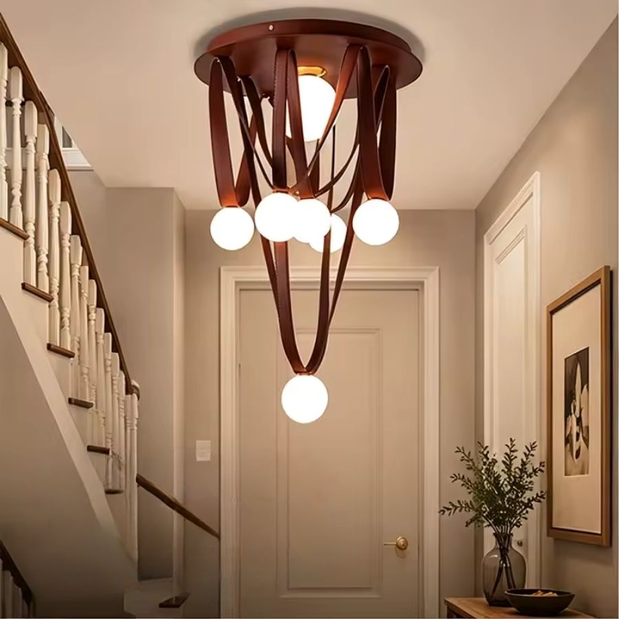 Dans une entrée élégante, les lanières de cuir brun et globes opalins forment un lustre sculptural et chaleureux