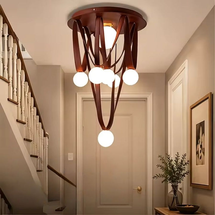 Dans une entrée élégante, les lanières de cuir brun et globes opalins forment un lustre sculptural et chaleureux