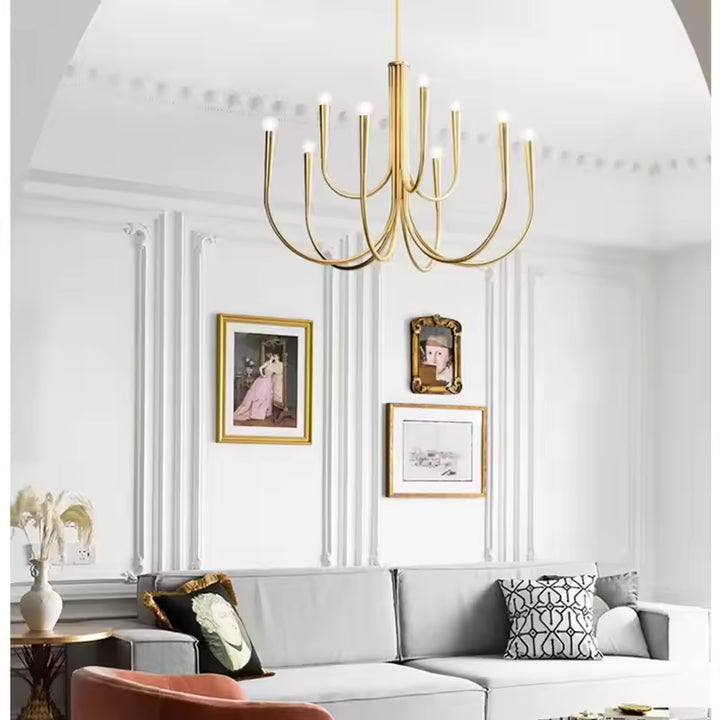 Dans un salon aux moulures élégantes, lustre doré à bras effilés et lignes courbes, mêlant design moderne et chic classique.