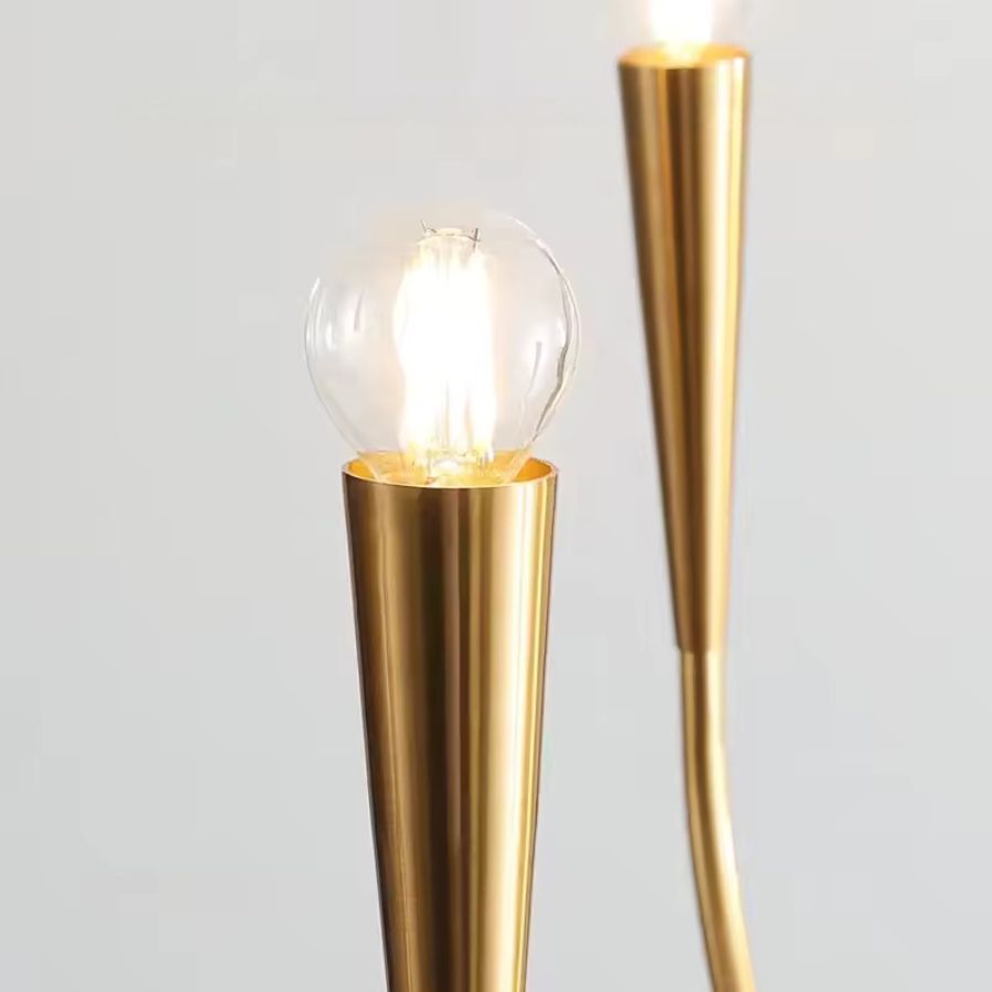 Gros plan sur une ampoule globe lumineuse et son support conique doré, détail élégant d'un lustre design minimaliste.