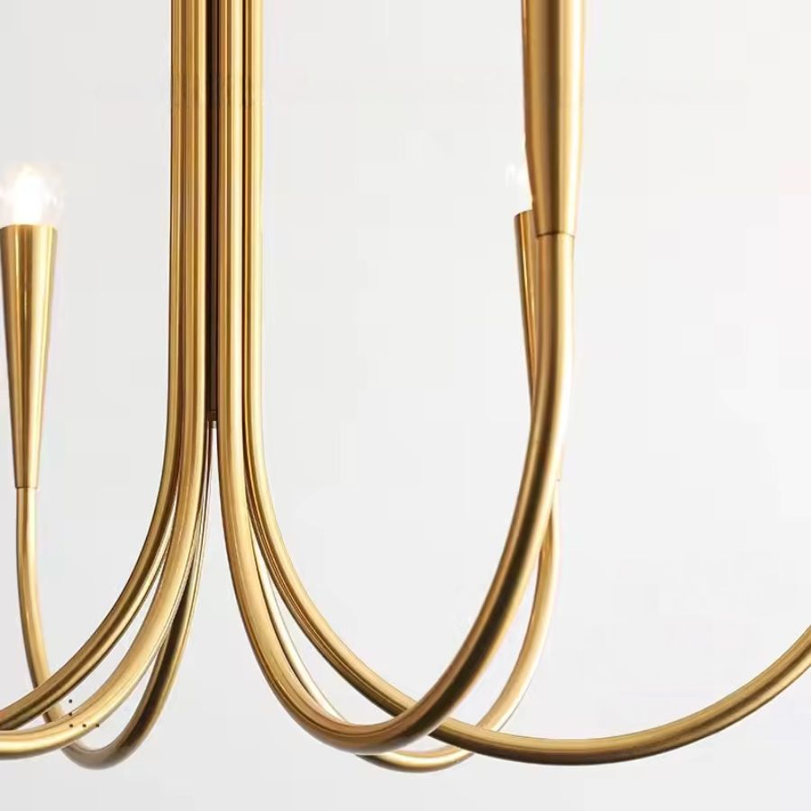 Détail des bras effilés en métal doré satiné d'un lustre design, aux courbes fluides et à l'esthétique contemporaine.