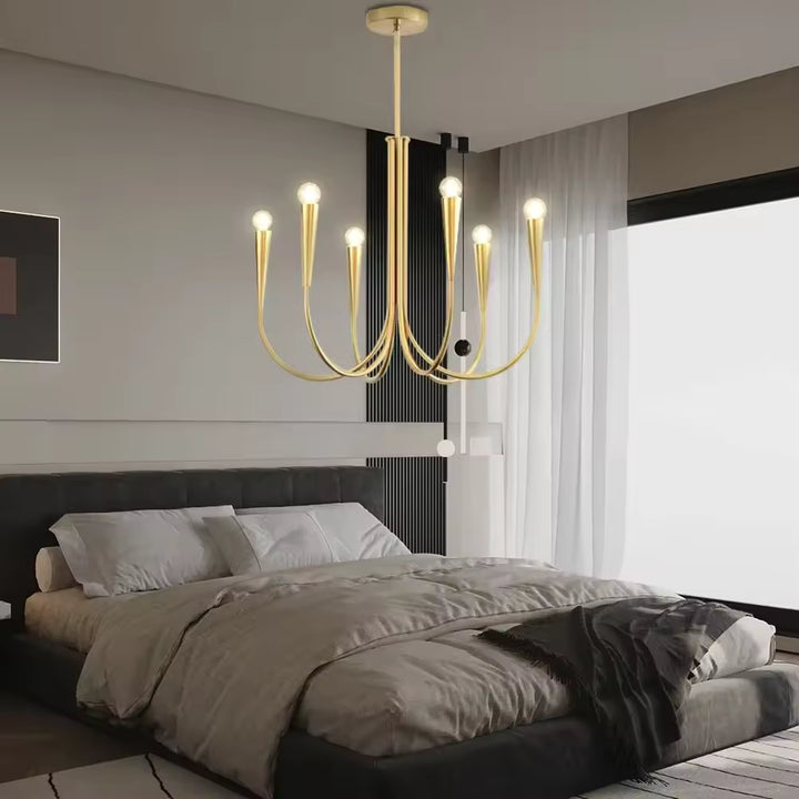 Au-dessus d'un lit double, lustre doré à six bras effilés et ampoules rondes, au style moderne et élégant.