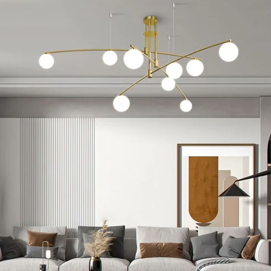 Un lustre sculptural doré aux branches élancées et globes lumineux sublime ce salon contemporain aux accents minimalistes.