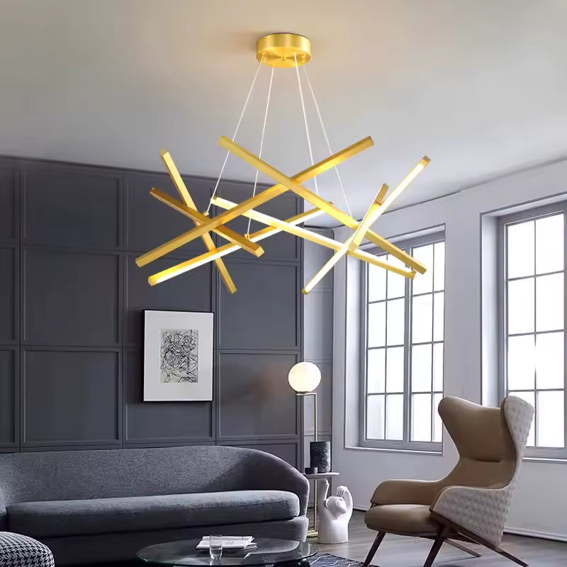Suspendu dans un salon élégant aux murs gris, ce lustre doré aux barres LED croisées affirme un style sculptural et raffiné.