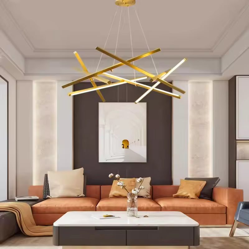 Un lustre doré aux tiges LED entrecroisées surplombe un canapé terracotta dans un salon chic au style contemporain.