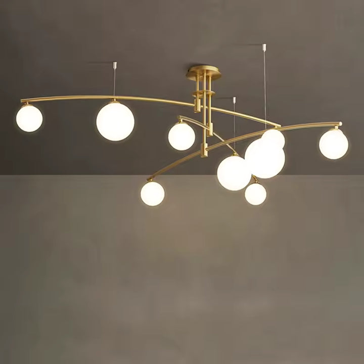 Déploiement de bras dorés incurvés et de globes lumineux en verre blanc sur un lustre aérien d'inspiration rétro chic.
