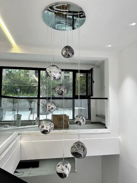 Lustre effet miroir en cascade de sphères chromées, parfait pour sublimer un haut plafond ou une cage d’escalier moderne.