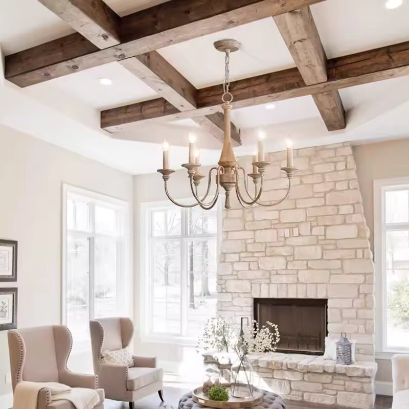 Sous des poutres apparentes, ce lustre en bois ancien à 6 bras galbés sublime un salon rustique chic avec cheminée en pierre.