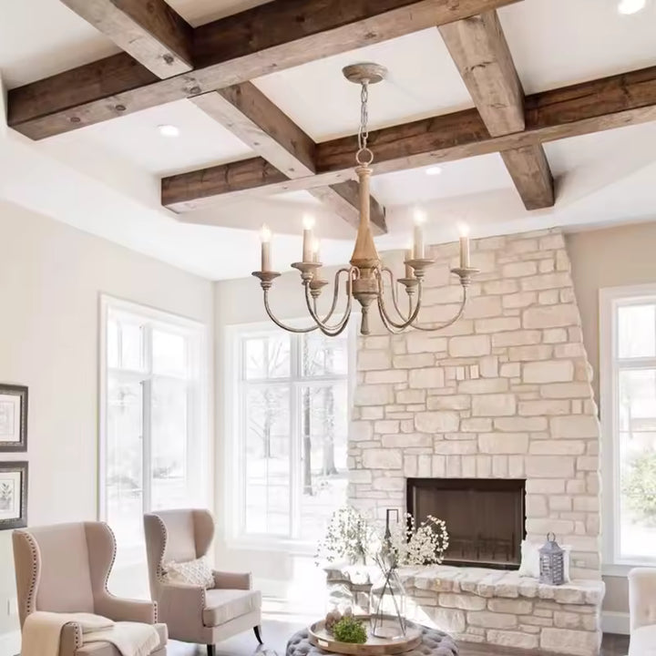 Sous des poutres apparentes, ce lustre en bois ancien à 6 bras galbés sublime un salon rustique chic avec cheminée en pierre.