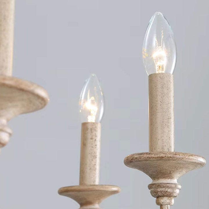 Détail des ampoules en forme de bougie et des supports beige patiné d'un lustre en bois ancien au style campagne chic.