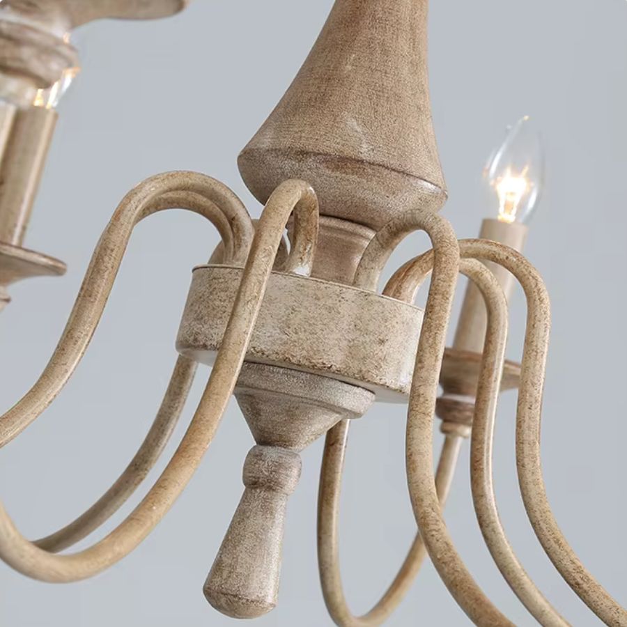 Gros plan sur le fût central et les bras courbés d'un lustre en bois ancien, à la finition beige patinée au charme rustique.