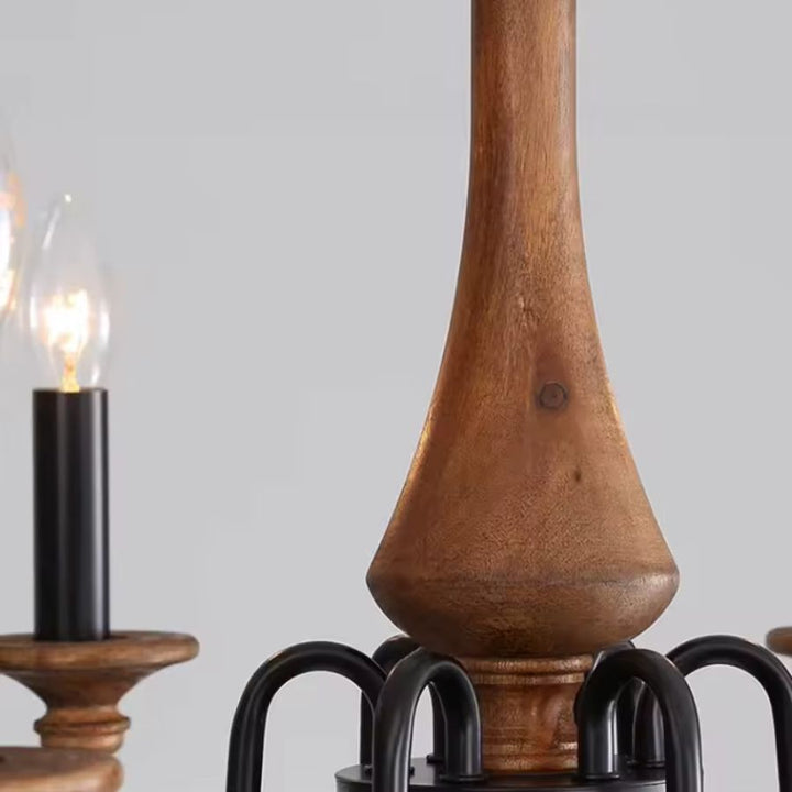 Gros plan sur le fût en bois brun et les bras noirs courbés d'un lustre en bois ancien, au style rustique et authentique.