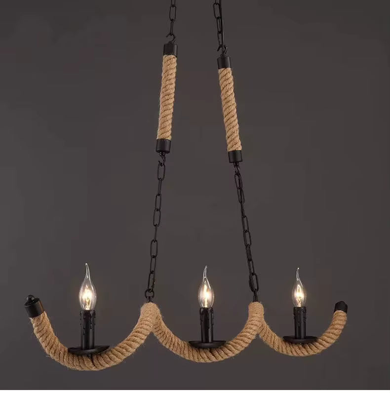 Trois ampoules flammes sur un lustre en corde de chanvre aux bras ondulés, avec chaînes noires au style industriel vintage.