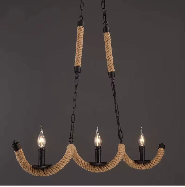 Trois ampoules flammes sur un lustre en corde de chanvre aux bras ondulés, avec chaînes noires au style industriel vintage.