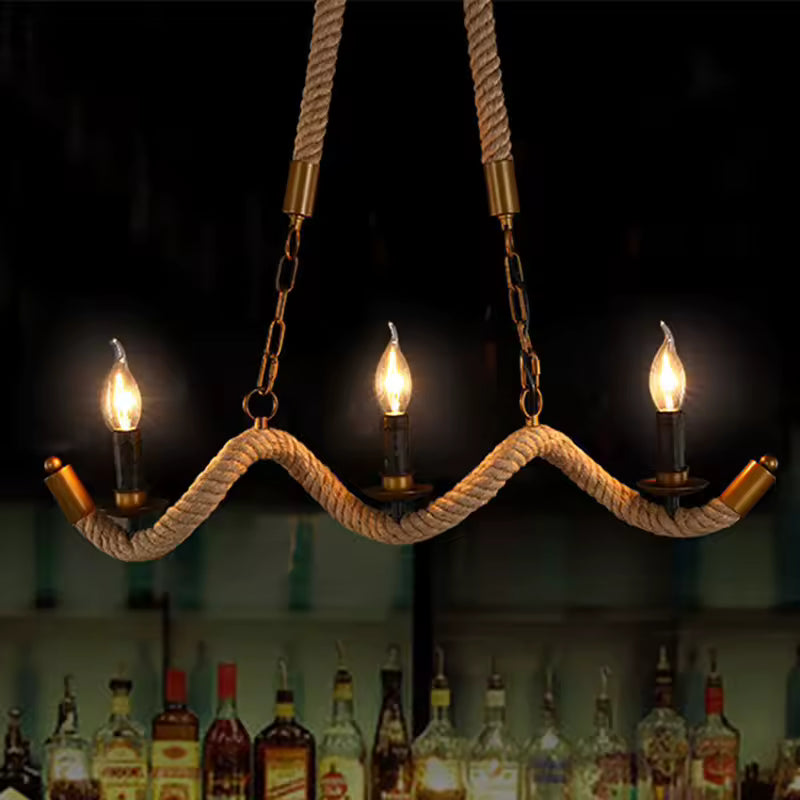 Sur fond sombre, un lustre en corde à bras ondulés et trois ampoules flammes crée une ambiance de bar vintage.