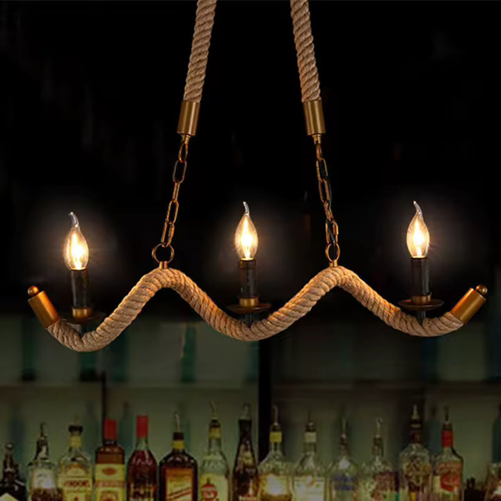 Sur fond sombre, un lustre en corde à bras ondulés et trois ampoules flammes crée une ambiance de bar vintage.